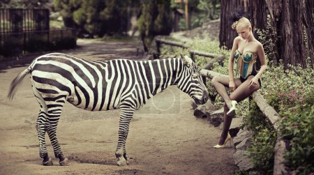 Beautiful lady sitting next to a zebra