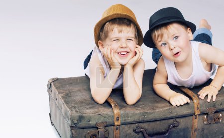 Two cute brothers lying on luggages
