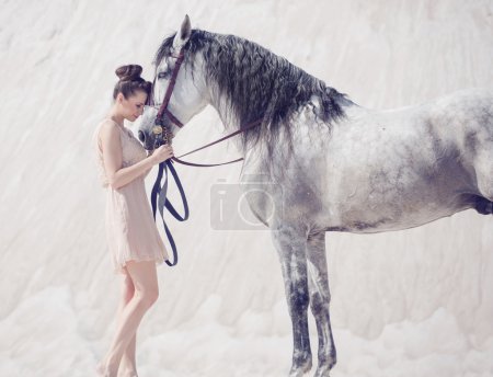 Beautiful young woman hugging the horse