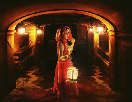 Romantic lady holding a lantern in a dark dungeon