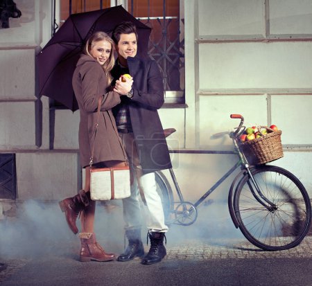 Elegant couple with umbrella on rainy evening