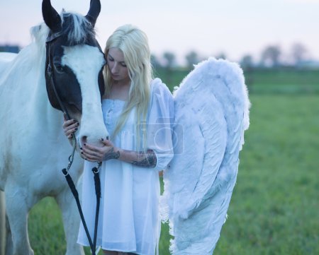 Blond angel looking after the horse