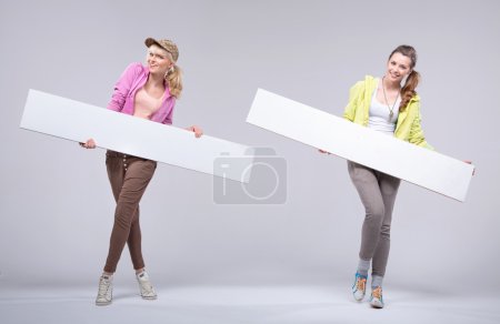 Two happy relaxed girlfriends with white boards