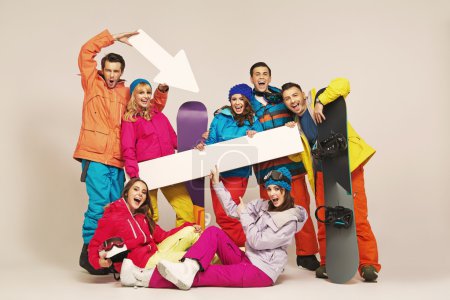 Cheerful snowboarders with fancy signs