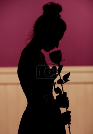 Young woman silhouette holding flower