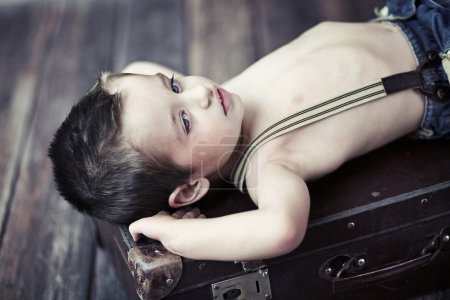 Child boy relaxing on the suitcase