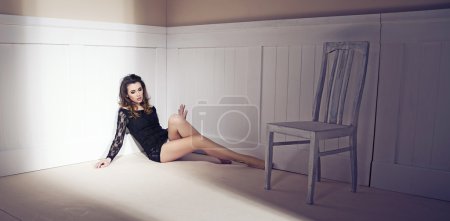 Sexy young woman with long legs sitting on a floor