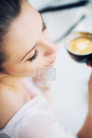 Nice picture of resting brunette woman holding a cup of coffee