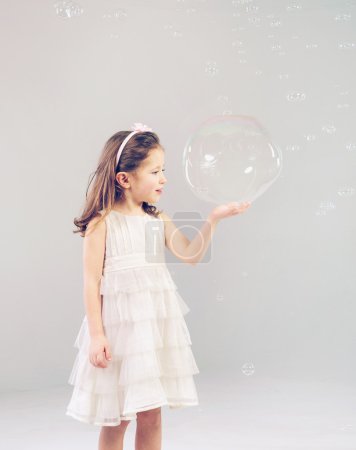Funny lovely little girl playing with soap bubbles