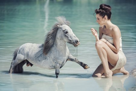 Alluring woman playing with the pony in the pool