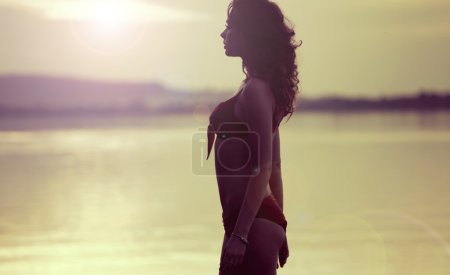Alluring brunette woman walking along the lakeside
