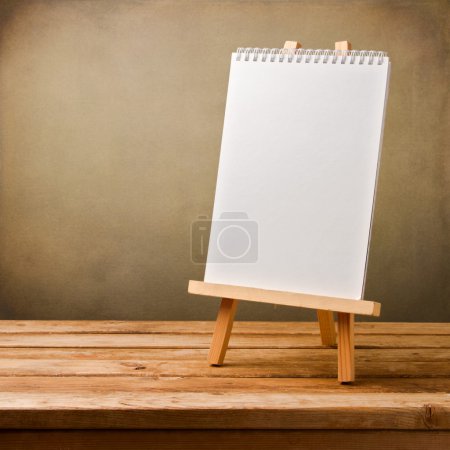 Blank note book on easel on wooden table