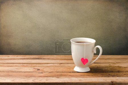 Cup of tea with heart shape on wooden table