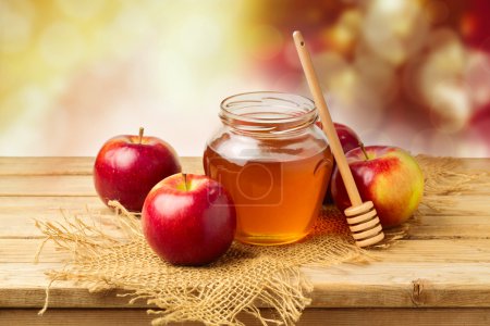 Apples with honey jar on wooden table