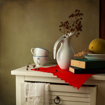 Still life with jug, books and watermelon on white table