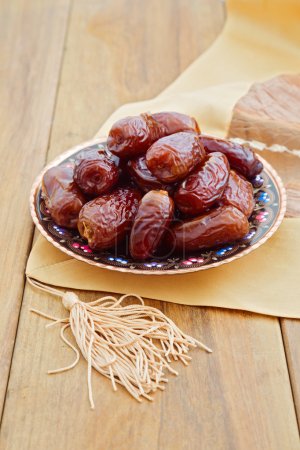 Dates on plate over wooden background
