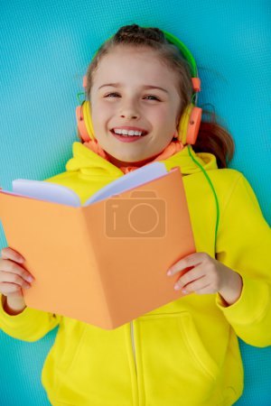 Young girl with headphones reading a book