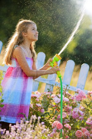 Summer fun, lovely girl watering flowers