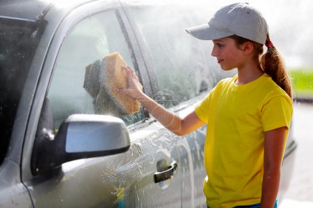 Car wash - a teenage girl washes the car