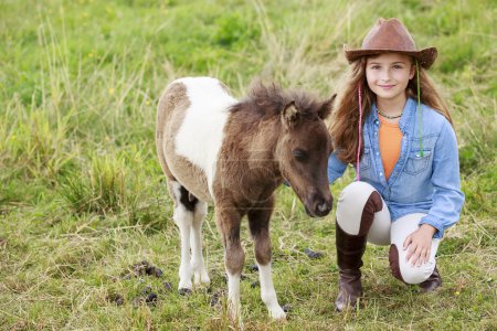 Little foal and girl - cute girl takes care of the pony foal