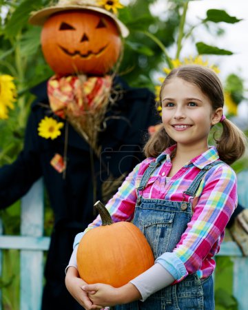 Scarecrow and happy girl  in the garden - Autumn harvests
