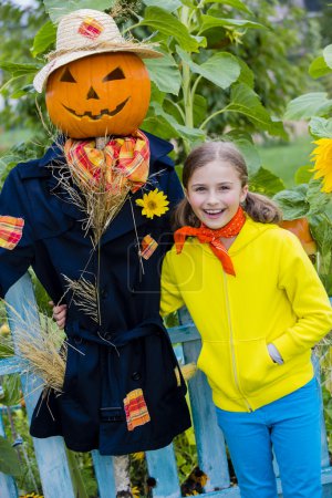 Halloween, Scarecrow and happy girl  in the garden