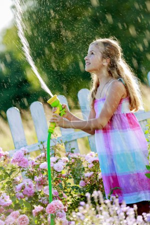 Summer fun, lovely girl watering flowers