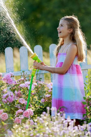 Watering, flower garden - beautiful girl watering roses