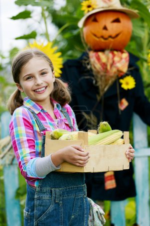 Scarecrow and happy girl  in the garden - Autumn harvests