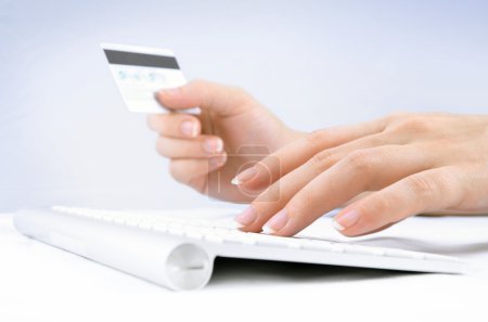 Woman's hands holding a credit card and using computer keyboard for online shopping