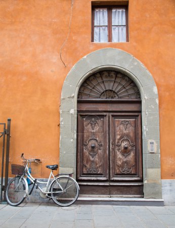 Bicycle Outside Brown Doors on Orange Plaster