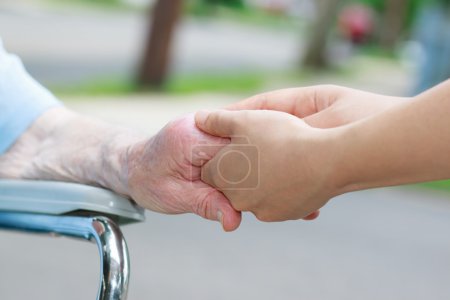Caregiver holding elderly womans hand