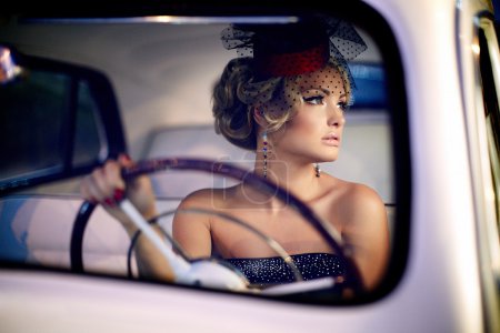 Beautiful sexy woman sitting in old car in retro style