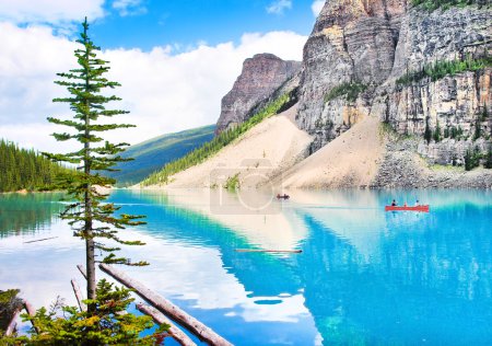 Beautiful landscape with Rocky Mountains and tourists canoeing on azure mountain lake, Alberta, Canada
