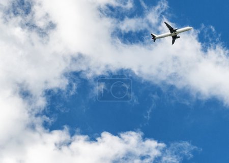 Airplane over cloudy sky background