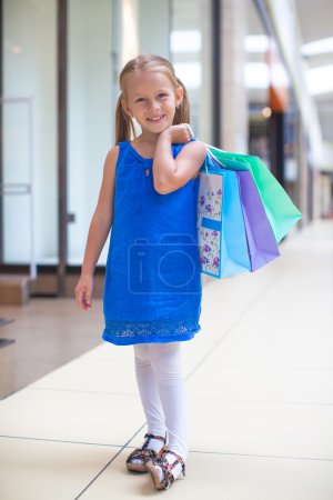 Little happy girl with packages in a large shopping center