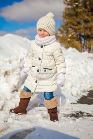 Little cute happy girl having fun in the snow on a sunny winter day