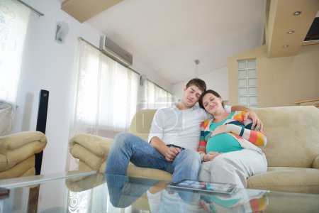Pregnant couple at home using tablet computer