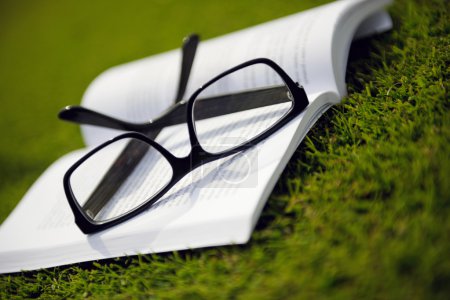 Glasses on a book outside with grass
