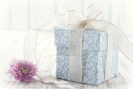 Gift box tied up with white ribbon and pink flower