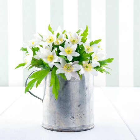 Spring wild flowers in a metal cup on vintage background