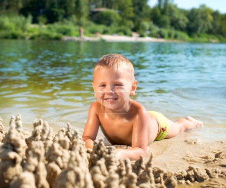 Happy kid playing at the beach in summer. River