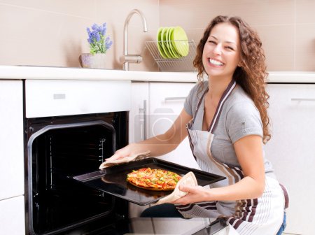 Happy Young Woman Cooking Pizza at Home