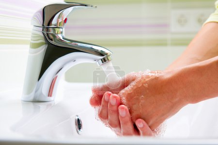 Woman Cleaning Hands in a Bathroom