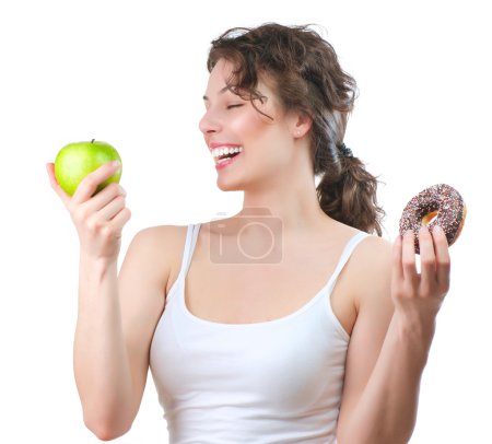 Diet. Beautiful Young Woman choosing between Fruit and Donut