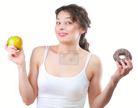 Diet. Beautiful Young Woman choosing between Fruit and Donut