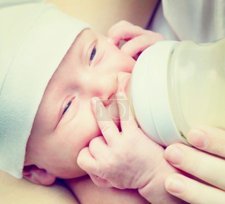 Feeding Baby. Newborn Baby eating milk from the bottle
