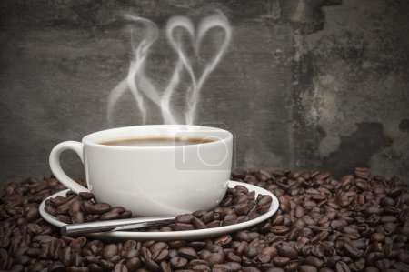 Hot coffee with heart shaped smoke, surrounded by coffee beans i