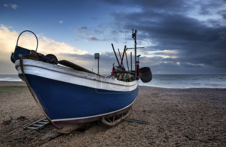 Fishing boat on beach landscape with stormy sky