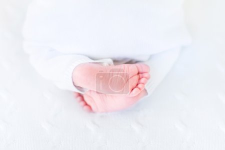 Tiny baby feet on a white knitted blanket